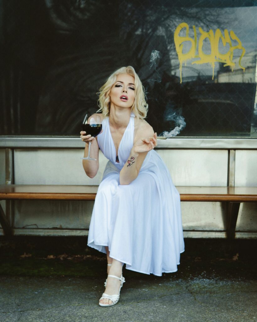 Model Dressed as Marilyn Monroe with a Glass of Wine and a Cigarillo Sitting at a Bus Stop